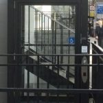 Black hydraulic lift in front of black railings