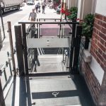 Mira low-rise platform lift with a closed gate outside a building on a busy road