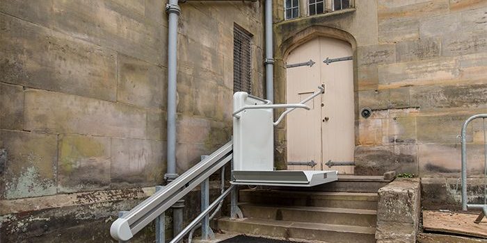 An inclined platform lift in use down a few steps outside Scotney Castle