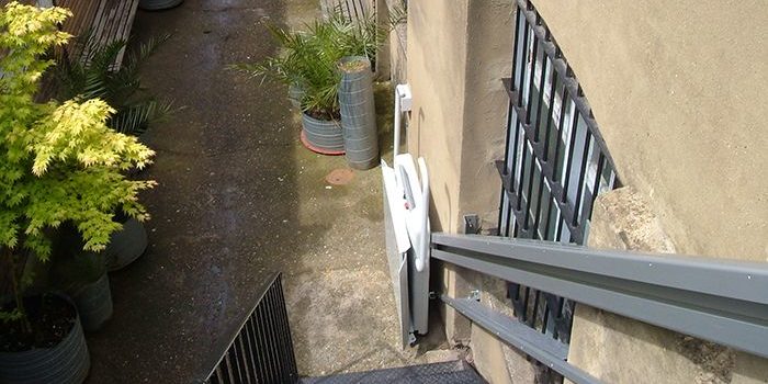 A top-down view of an inclined platform lift at the base of an external staircase