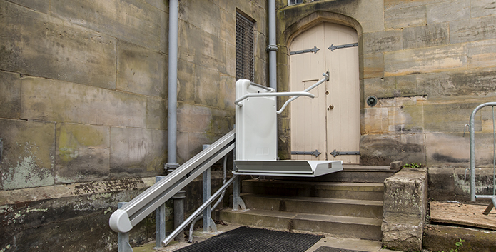 An inclined platform lift assiting mobility down a few steps outside Scotney Castle